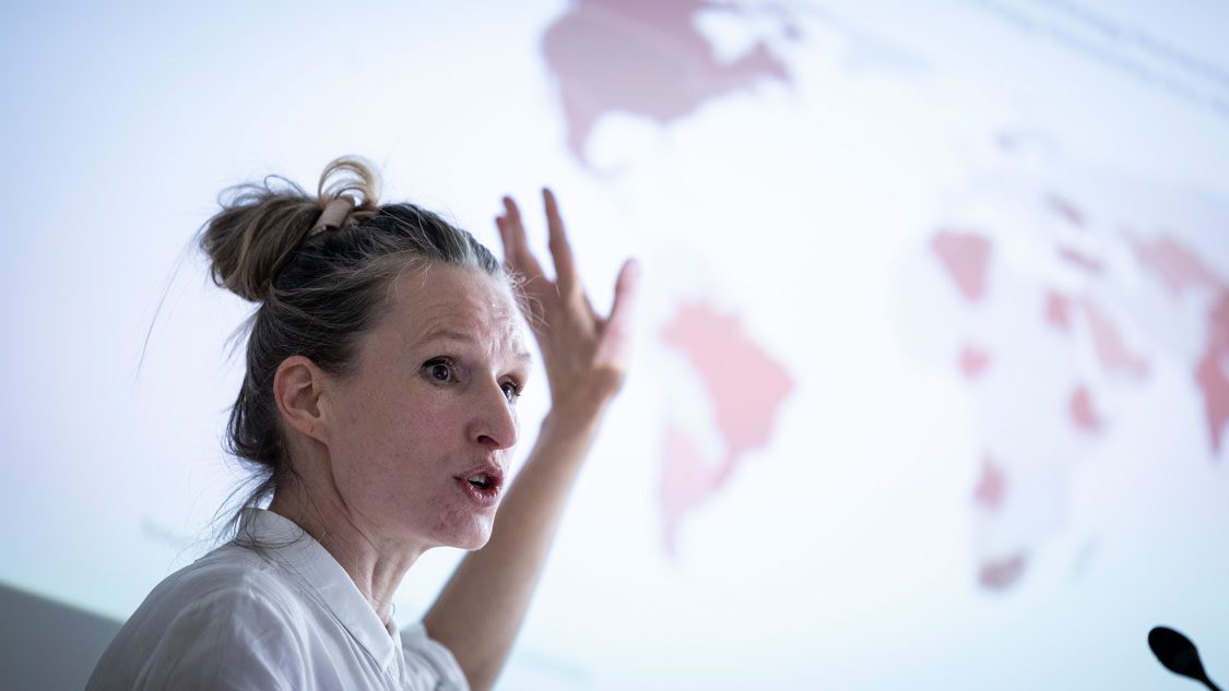Speaker presenting in front of a projected world map in Bonn
