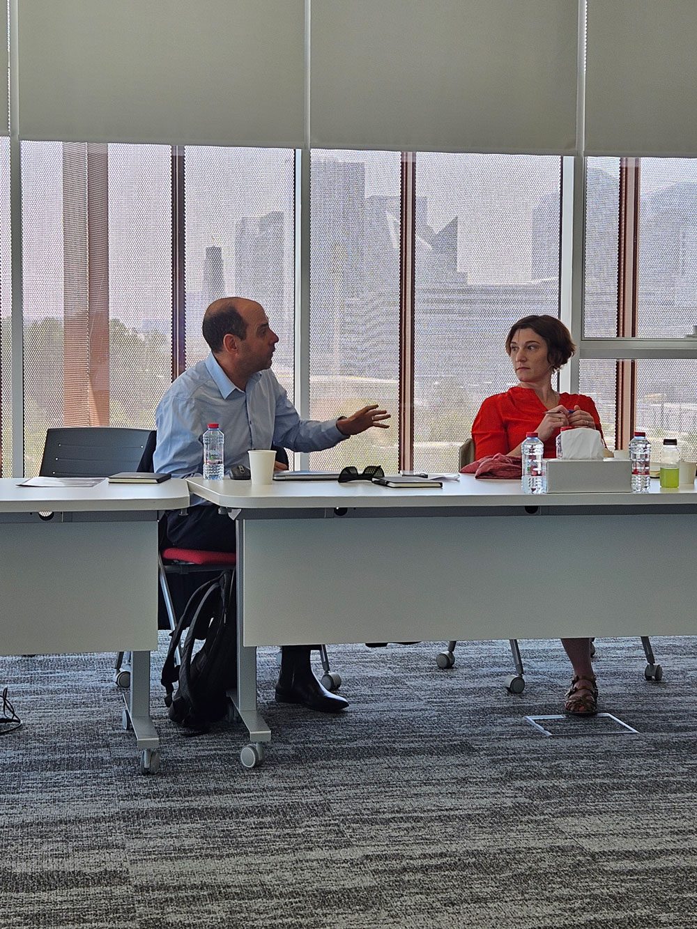 Two participants in discussion in Abu Dhabi, the skyline behind them